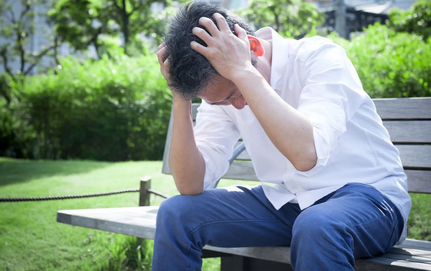 頭を抱えて悩む男性の写真。男性の腹圧性尿失禁の原因に関するイメージ