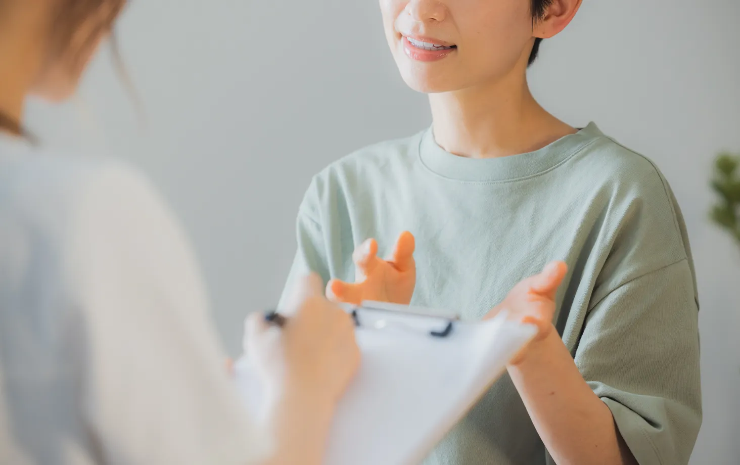 問診で症状を説明する女性と記録する医療者