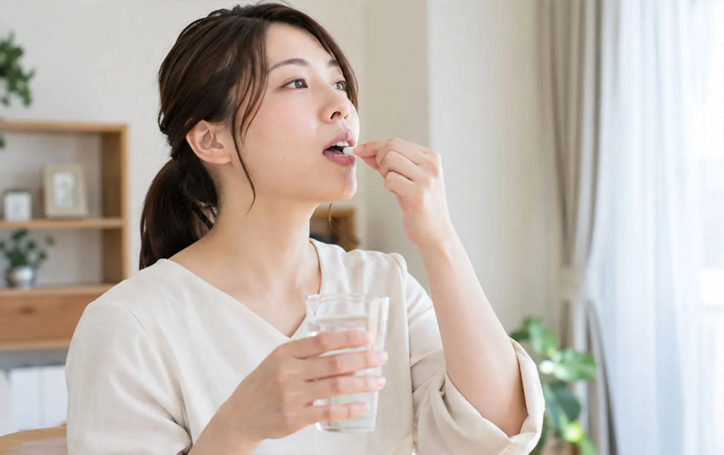 水を持って薬を飲む女性